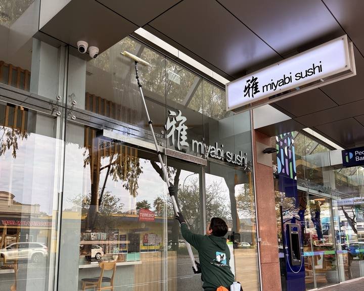 A Shiny Window cleaner using a water-fed pole on an Adelaide shopfront's glass.